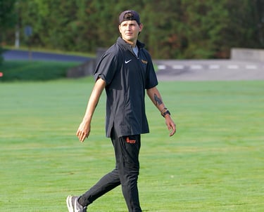 A smoldering photo of XC and Track and Field coach Justin Watson casually strolling across a field