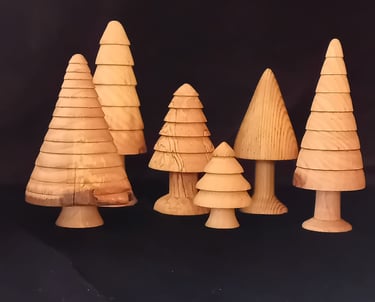 A group of golden-coloured turned wooden trees against a black background.