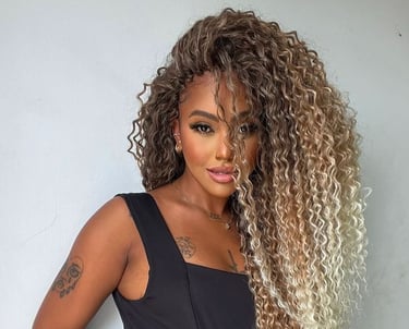 a woman with long curly hair (tree braids) and a black dress