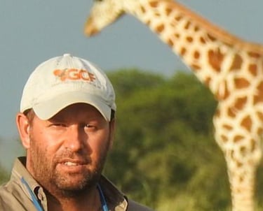 Dr Julian Fennessy in the bush with giraffe in background