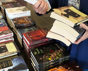 a woman is holding a book and a stack of books shopping at book event or book festival