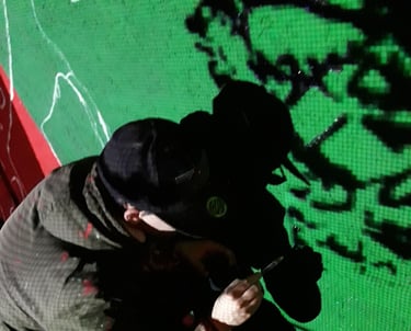 Artist working on a green-wall mural at night, an urban painting created by Poliops.
