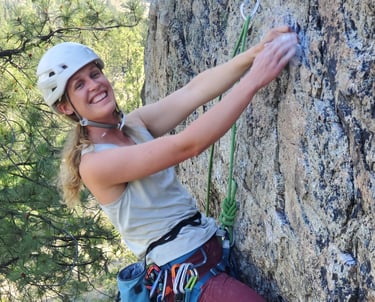 A smiling woman climbing an outdoor rock face