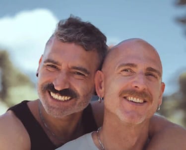 Dos hombres enamorados se abrazan felices frente a la cámara en una sesión fotográfica romántica LGBTQ+