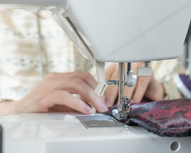 Gros plan sur des mains guidant le tissus sur une machine à coudre
