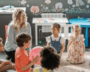 Happy children sitting in a circle, one with a large pink ball