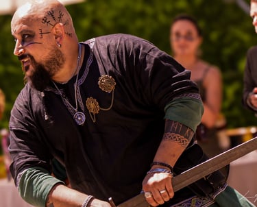 Hombre barbudo con tatuajes en el brazo sosteniendo una espada durante una celebración de boda temát