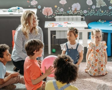 Happy children gather in a circle, one has a large pink ball