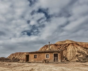Antigua cabaña de piedra solitaria junto a cerros erosionados en el paisaje desértico de Bardenas
