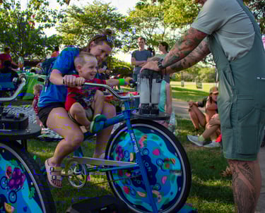 A little kid and a parent powering a smoothie on our blender bike