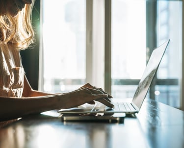 A woman with long blonde hair working on a laptop.
