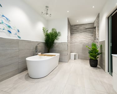 A large bathroom with freestanding bath. Pale grey tiles and white walls.
