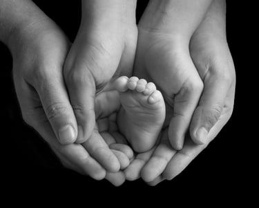 los papás de un bebé sosteniéndolo con sus manos