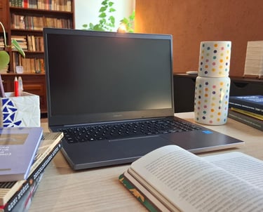 Mesa de trabalho com livros de autoras como Ana Suy, Gayle Rubin e Geni Núñez, ao lado do notebook u