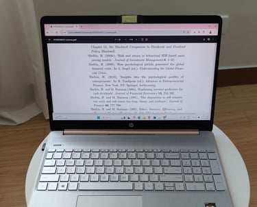 Silver HP laptop on a white table displaying a PDF, with a chiclet keyboard and wooden background.