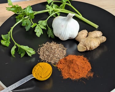Fresh aromatics prepared for cooking, including ginger, garlic, spices and herbs