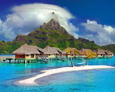 Bora Bora houses on water with mountain peak in distance