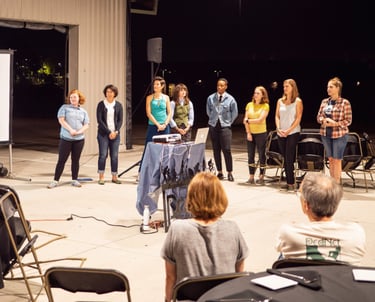 Staff members lined up in front of an audience, giving a presentation