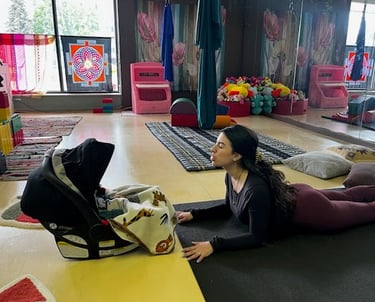 Mother in Sphinx Pose with infant in a car seat in front of her