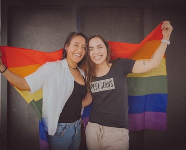 "Pareja lesbiana celebrando su amor con la bandera LGBTQ+ en un evento de orgullo."