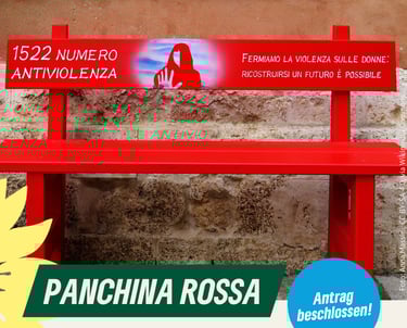 Foto einer roten Parkbank vor einer Mauer.