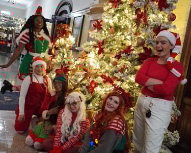 Holiday elves pose around a Christmas tree