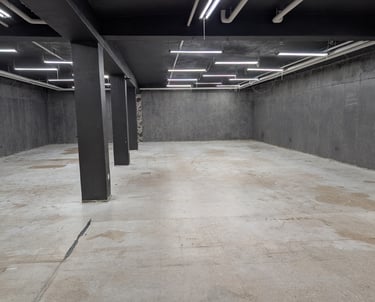 Large well lit basement studio with a concrete floor and grey walls