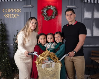 una familia de 5, mamá, papá y 3 hijas en un set navideño