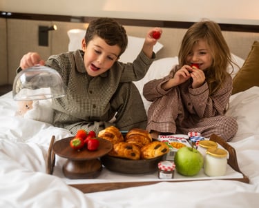 Enfants au petit déjeuner sur un lit de chambre d'hôtel