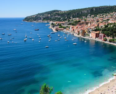 Coast of Villefranche sur mer coast with blue water, beach, sailboats and housing