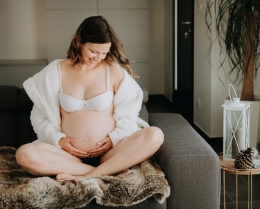 une femme enceinte assise sur son canapé 