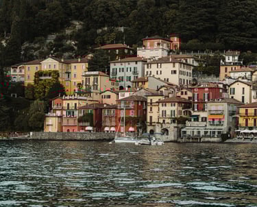 a bunch of houses on a hill with a boat in the water varenna lake como