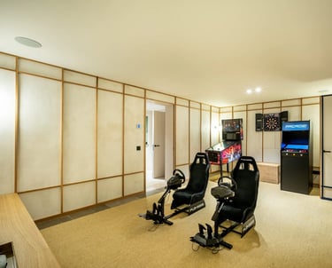 Game room at Villa La Gratitud with racing simulators, arcade machines, and darts