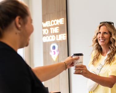 a woman is handing a cup of coffee to a customer