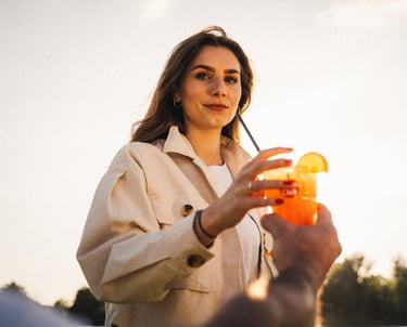 Frau greift bei Sonnenuntergang nach einem Cocktailglas – warmer Lichtmoment, filmische, ruhig