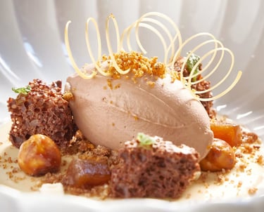 Plated dessert with chocolate ice cream, honeycomb, and caramel garnish.