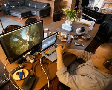 a man sitting at a desk with a laptop and a computer monitor editing a youtube video