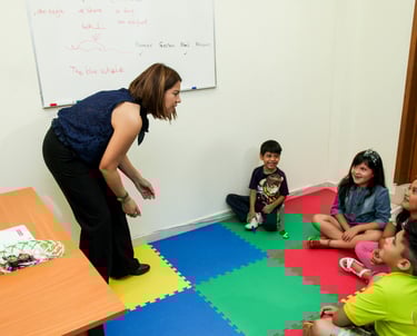 a woman standing in front of a group of children