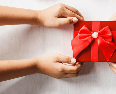 two hands holding a red gift box with a bow