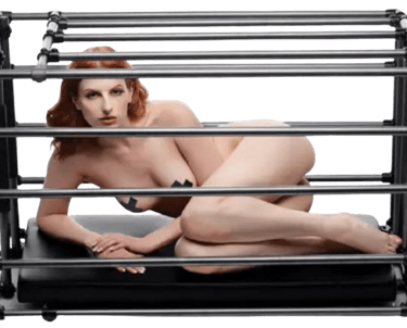 a woman in a fetish cage caged not wearing clothes but black tape over nipples 