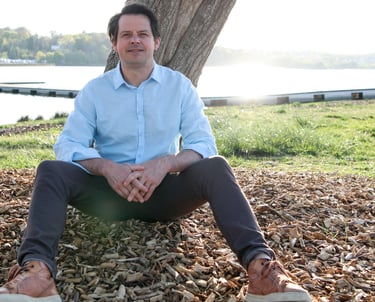 Un homme souriant qui pose, adossé à un arbre