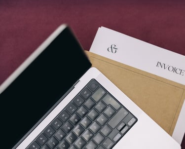 An open laptop on top of paperowrk on a desk.
