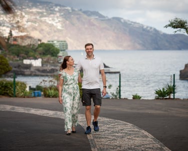 Couple walks along Funchal Lido Promenade, Madeira, with Atlantic coast and scenic cliffs in the background, lifestyle mood.