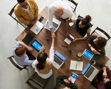 a group of people sitting around a table with laptops