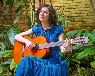chanteuse guitariste en robe bleue chantant dans une serre