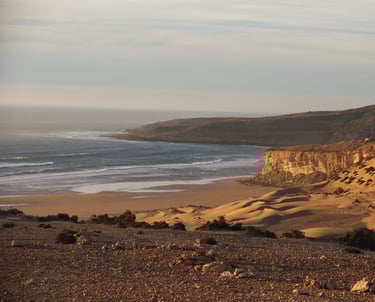 Plage magnifique au coucher de soleil avec l'océan, des dunes de sable et des falaises