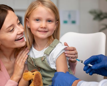 a girl sitting on her mother's lap receiving a vaccine from a healthcare professional