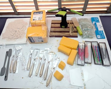 Art artist's drawing table filled with sculpture relief tools, sponges, clay sculpting tools, silicone kitchen spatulas.