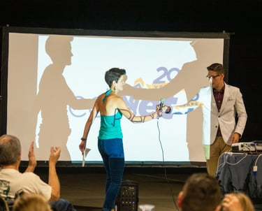 Two people exchanging a microphone in front of a screen