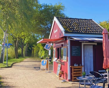 Der kleine Imbiss "Seeperle" am Plöner See mit Sonnenschein und Blick auf den Wanderweg